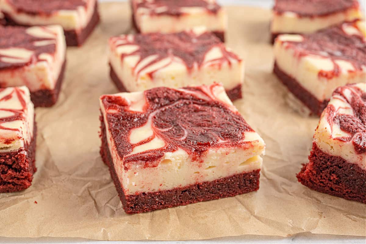 Red velvet cheesecake brownies cut into squares on parchment paper.