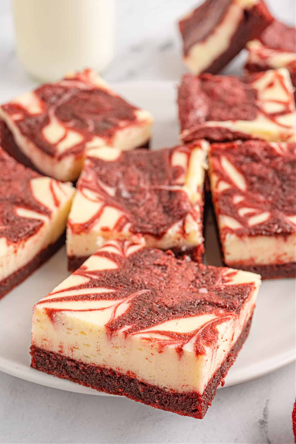Red velvet cheesecake bars served on a white plate.