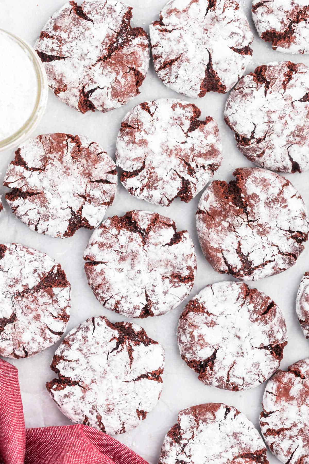 Red velvet crinkle cookies on a parchment paper lined cookie sheet.