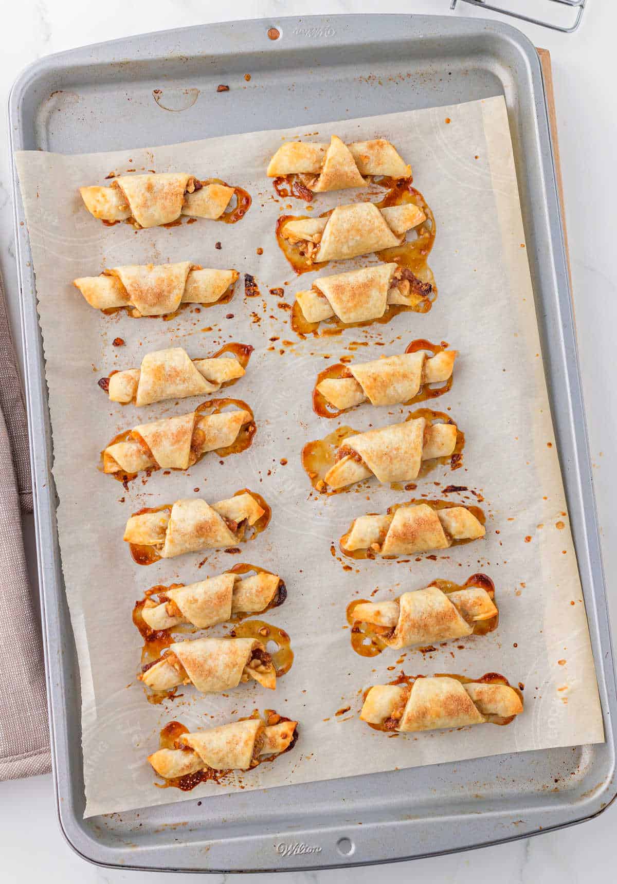 Rugelach cookies baked on a parchment paper lined cookie sheet.