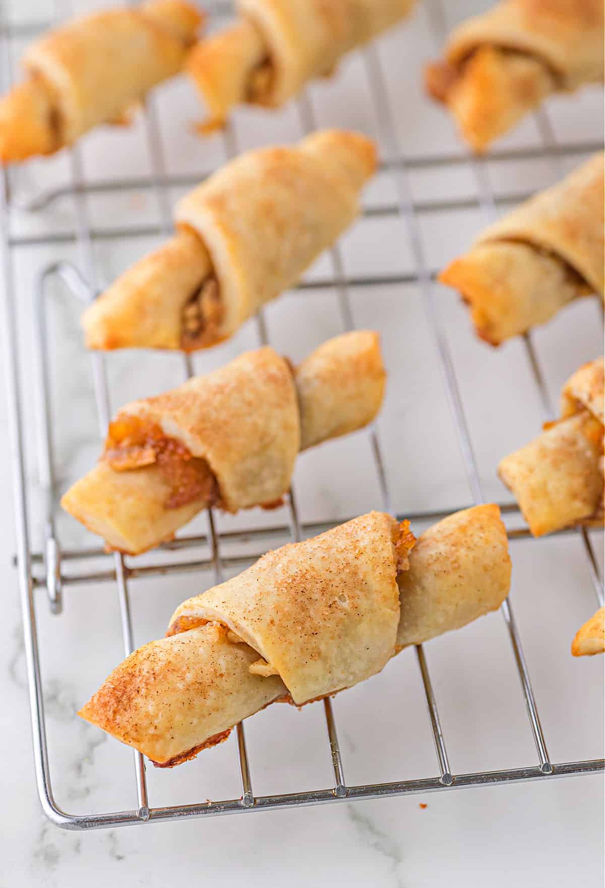 Baked rugelach cookies cooling on a wire rack.