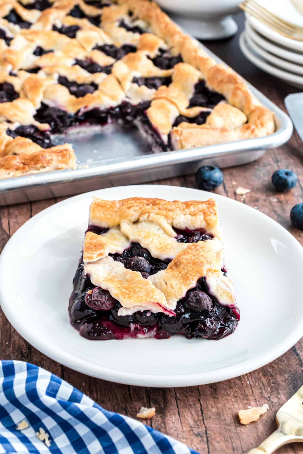 Slice of blueberry slab pie on a white plate.