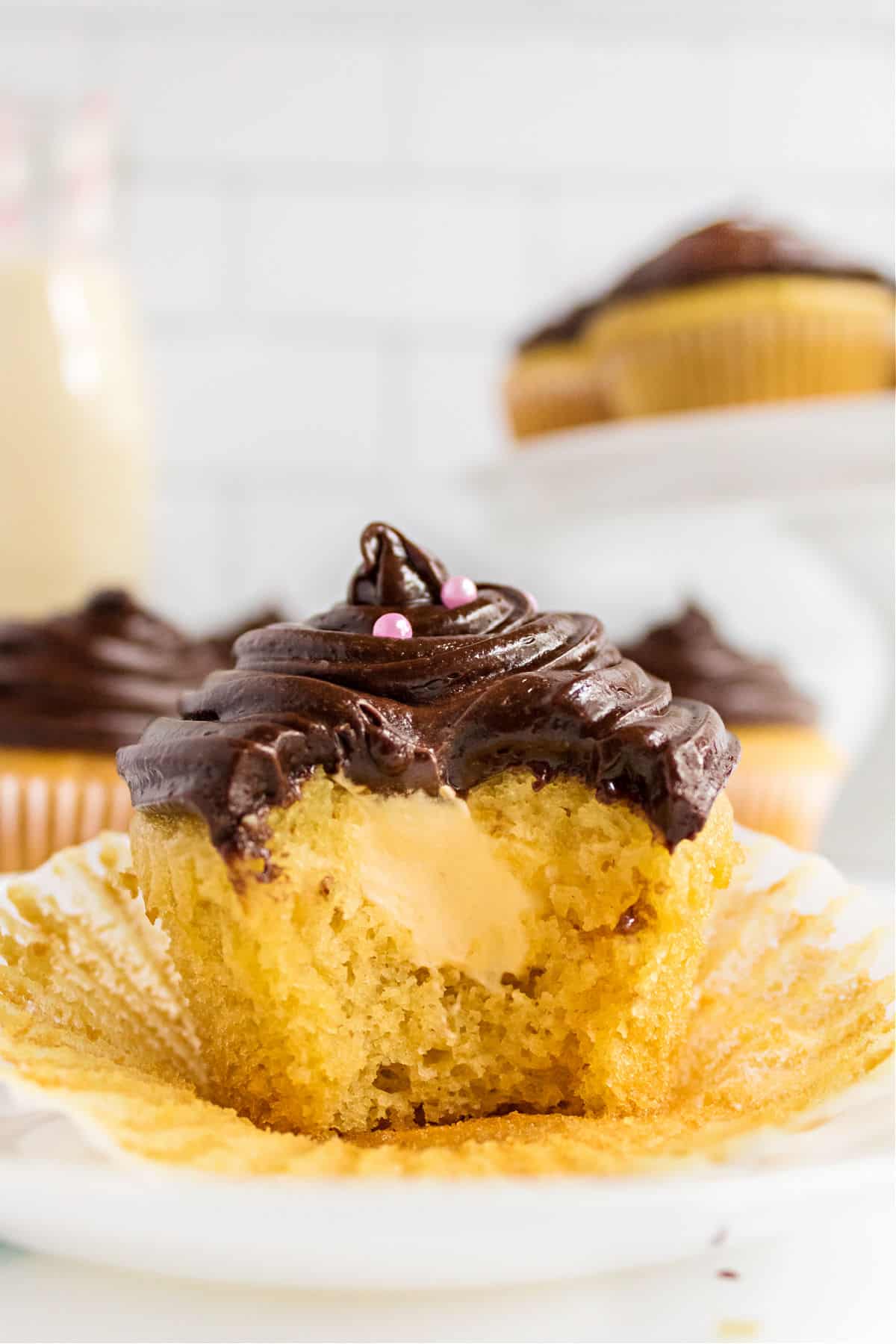 Boston cream cupcake with a bite taken out revealing vanilla custard filling.