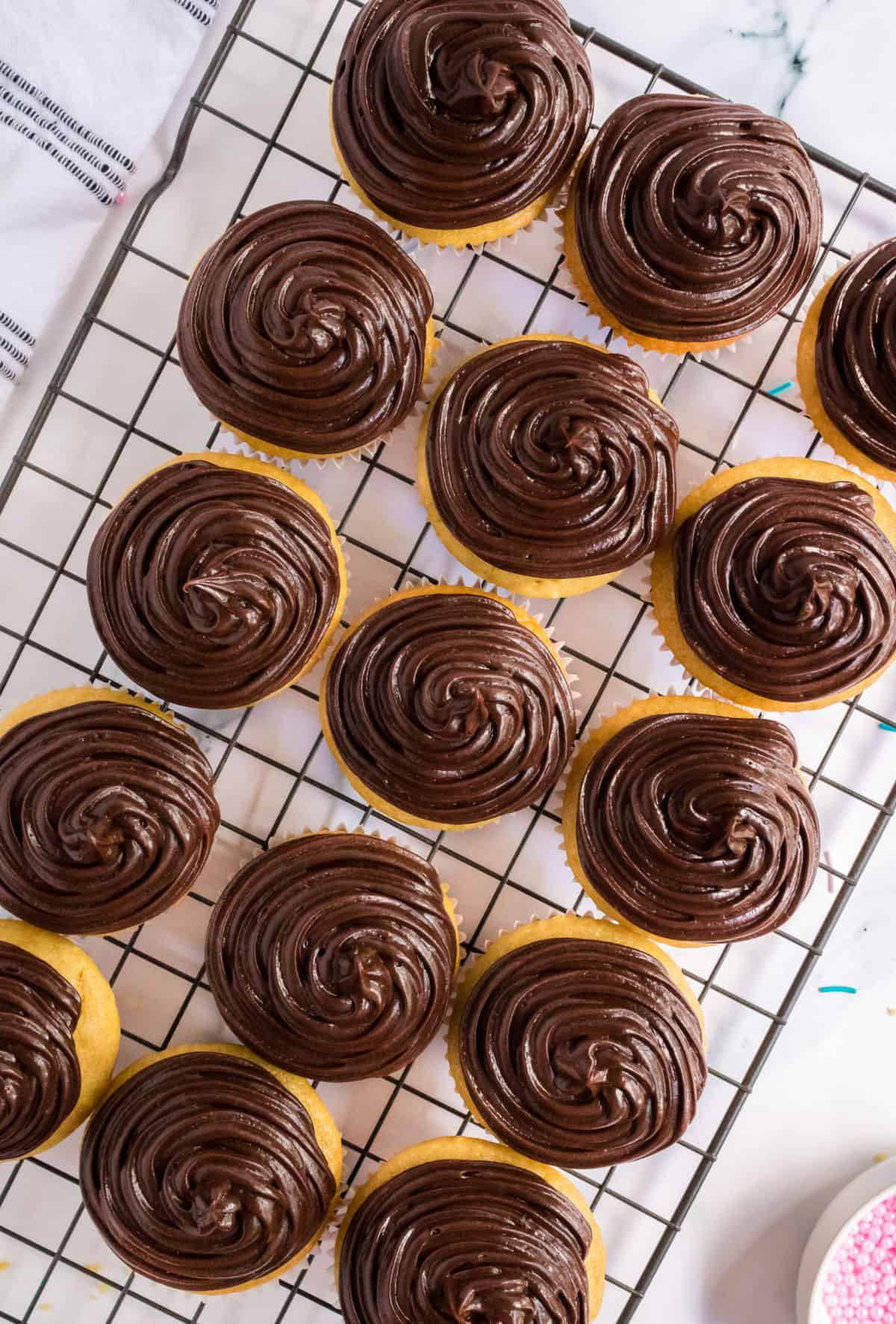 Chocolate frosted cupcakes on a wire cooling rack.