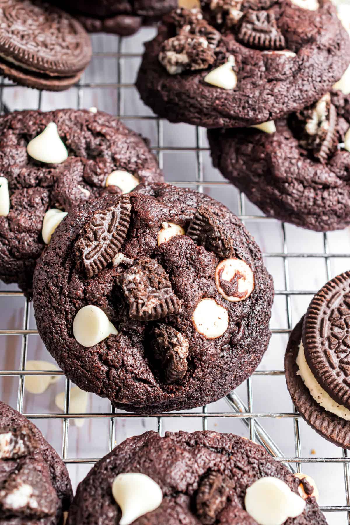 Chocolate oreo cookies stacked on a wire cooling rack.