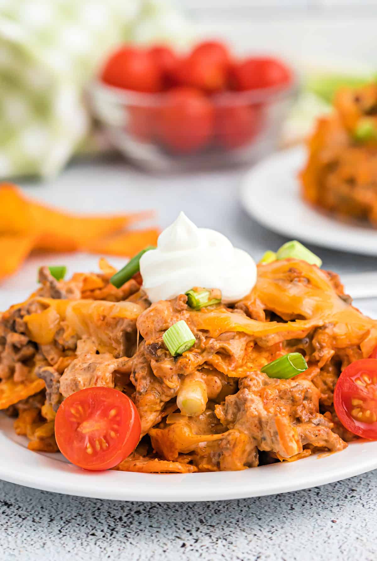 Doritos casserole served with green onion, sour cream, and tomatoes.