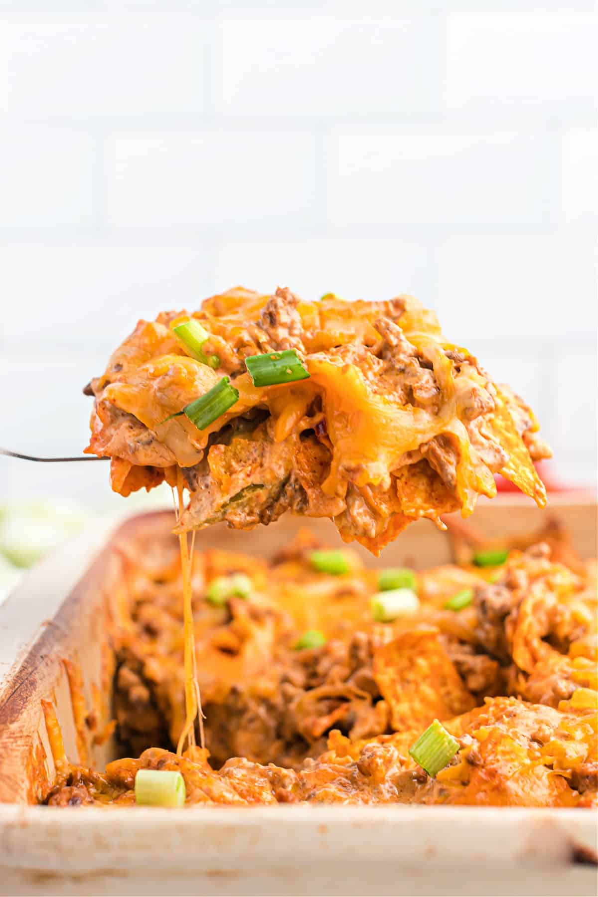 Scoop of Doritos casserole being spooned out of dish.