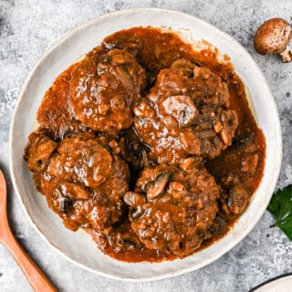 Salisbury steak in a white serving bowl with mushroom gravy.