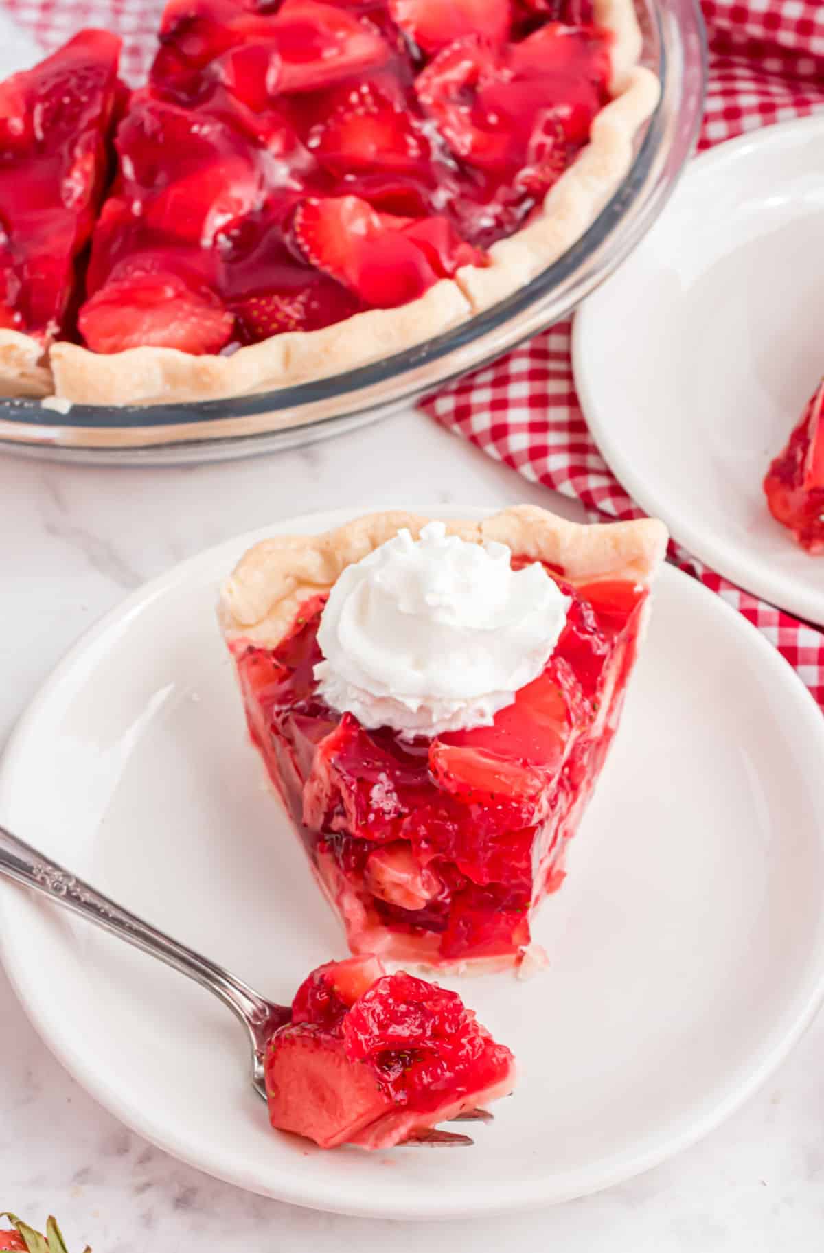 Strawberry pie on a plate with a bite taken out.