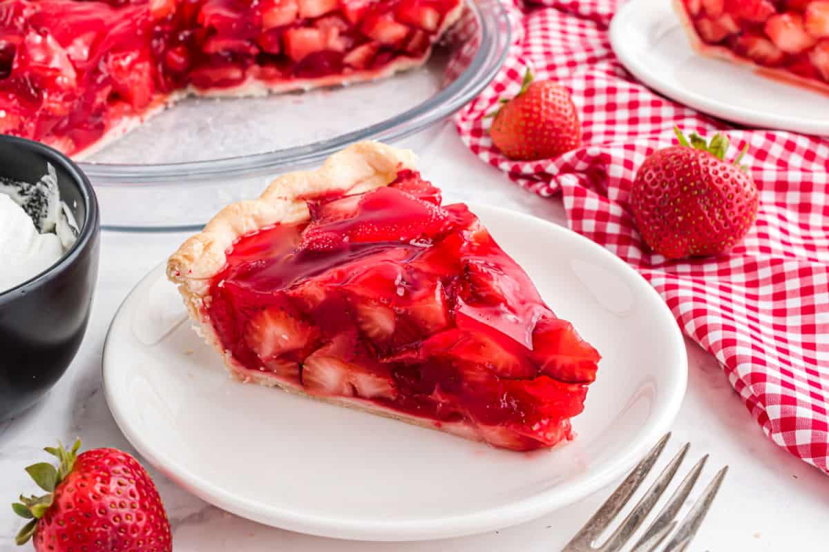 Slice of strawberry pie served on a white dessert plate.