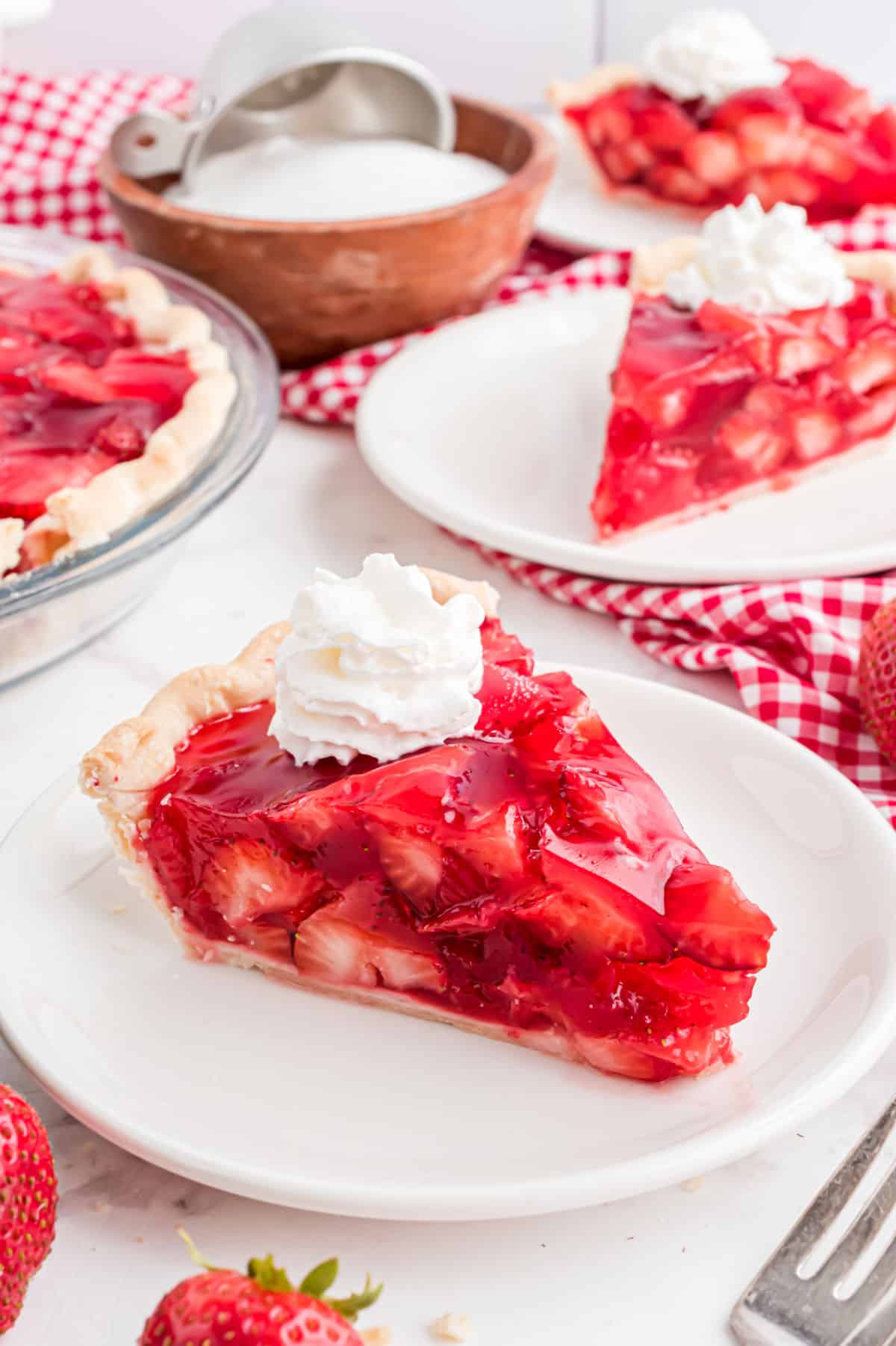 Slice of strawberry pie served with whipped cream.