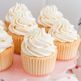 White cupcakes on pink cake platter.