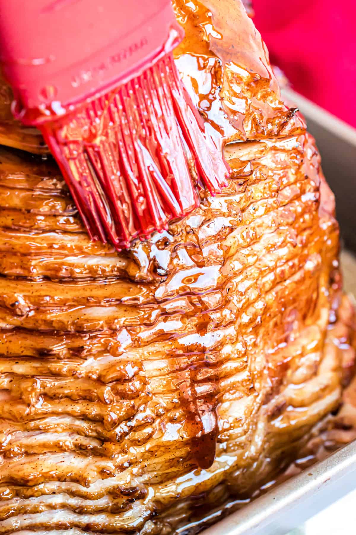 Brown sugar glaze being brushed onto a baked ham.