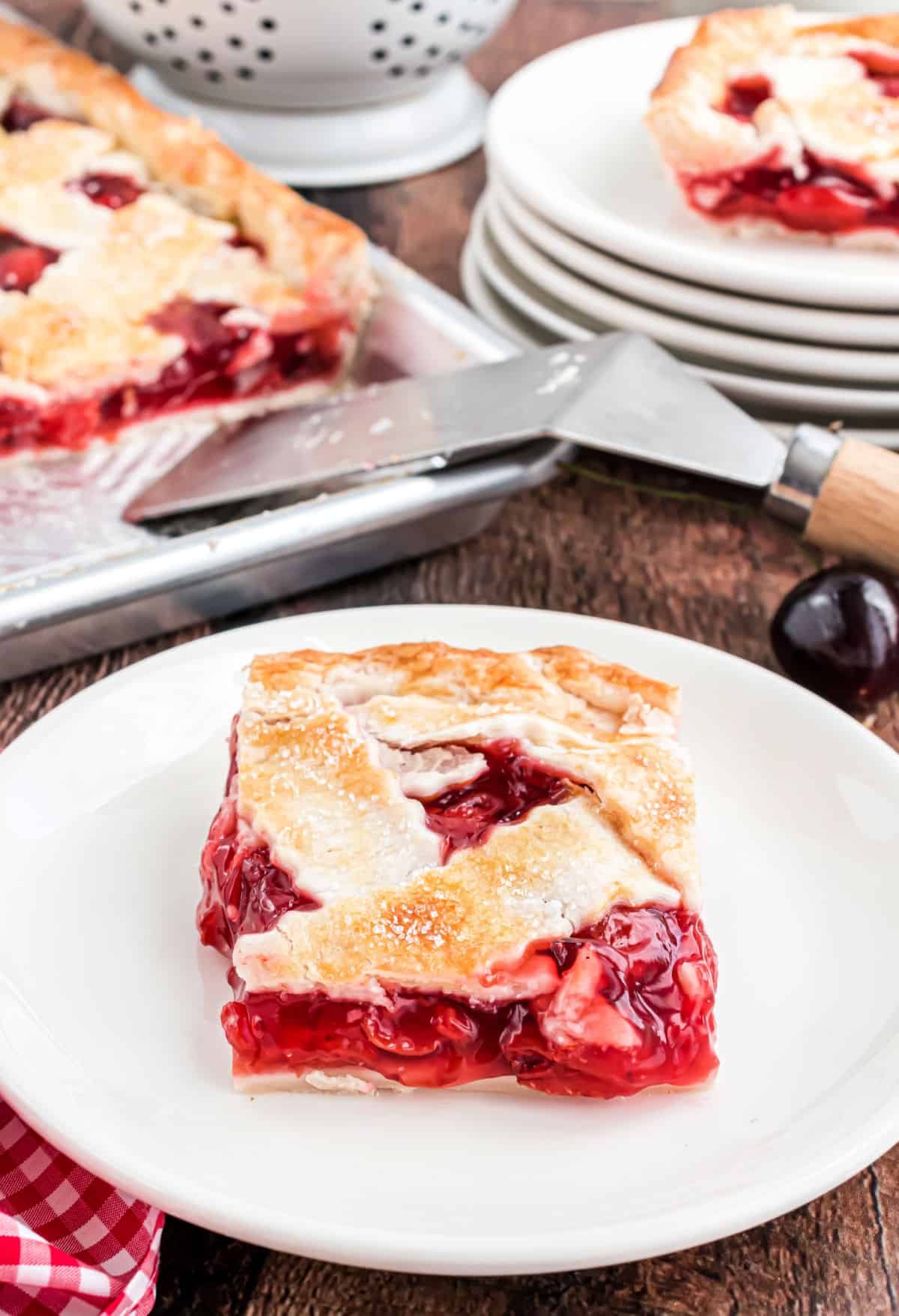 Slice of cherry pie on a white plate.