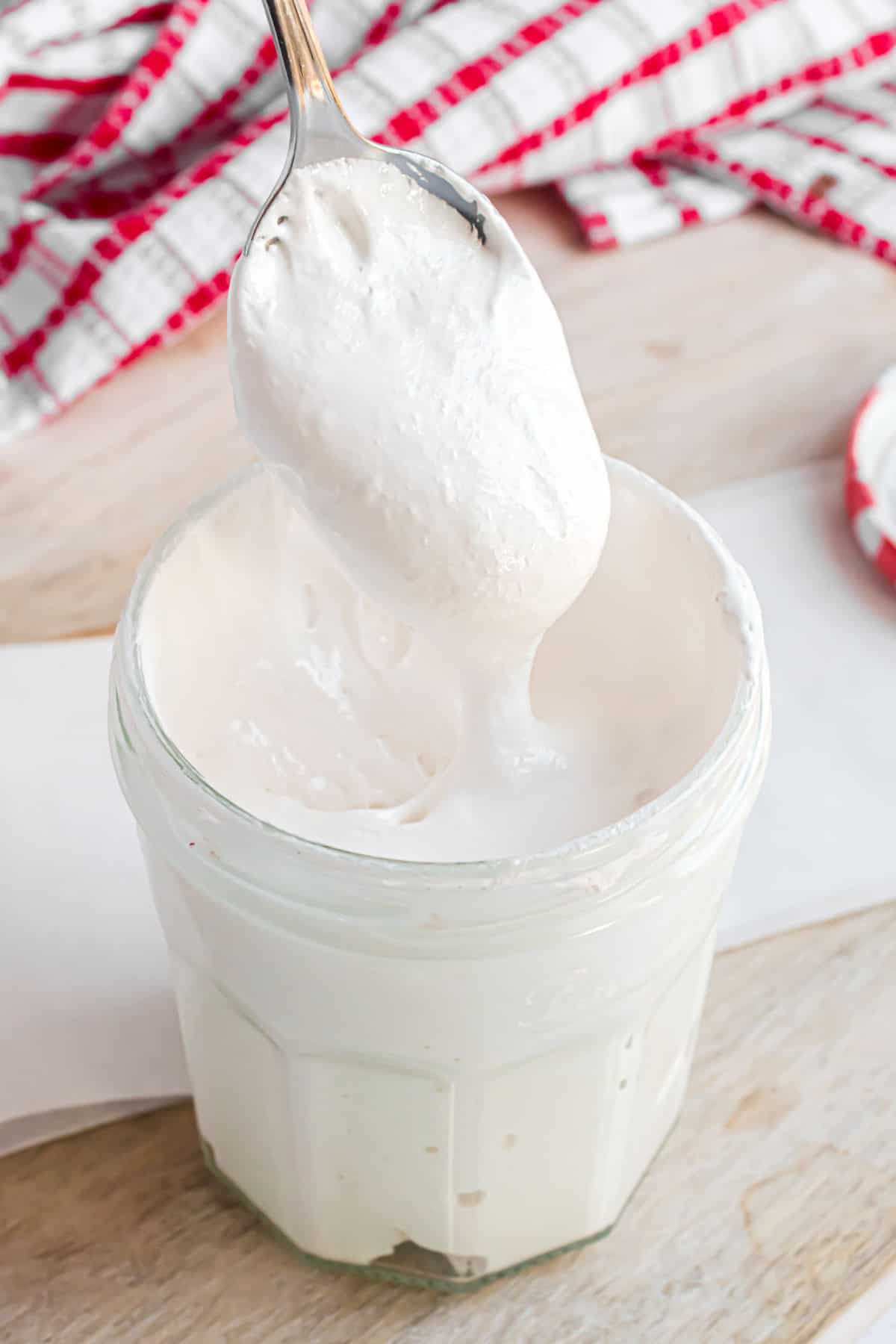 Homemade marshmallow fluff in a jar with a spoon.