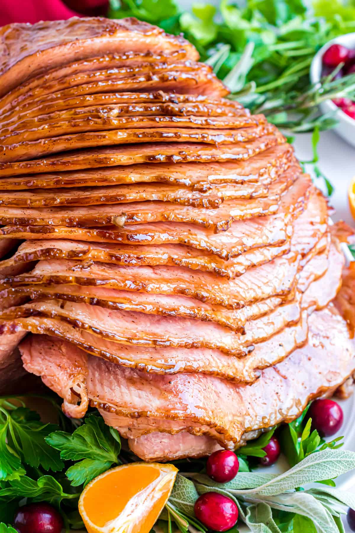 Spiral sliced baked ham on a large white  platter with a honey glaze.
