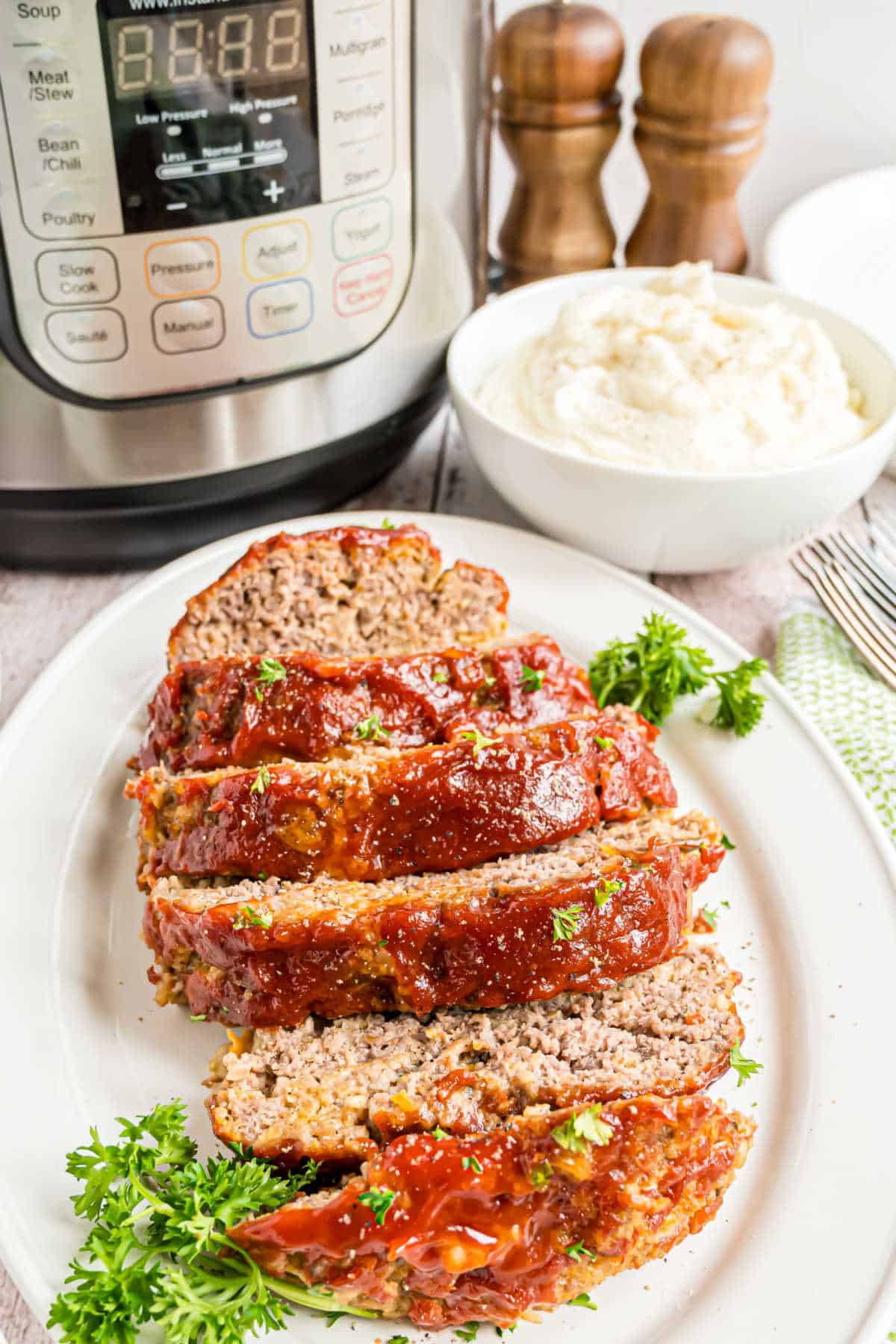 Sliced meatloaf on a serving plate with parsley garnish.