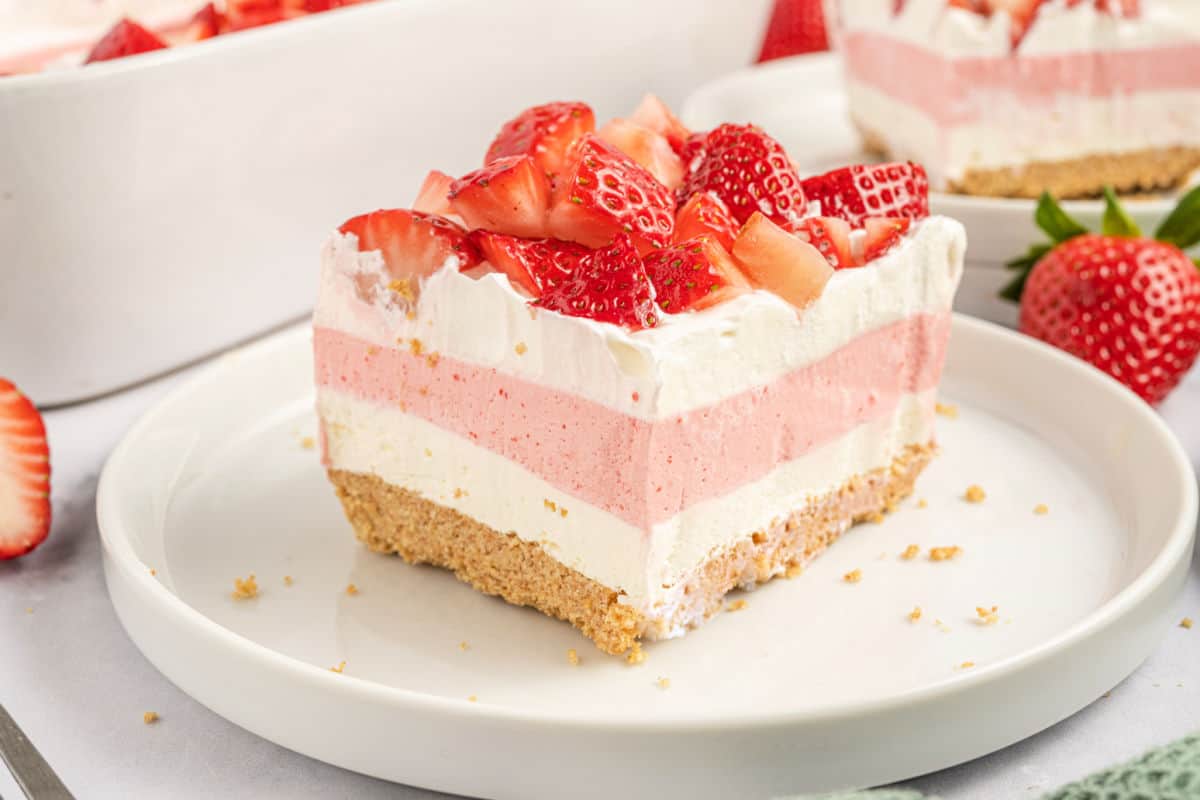 Slice of layered strawberry dessert on a white plate.