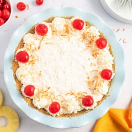 Pineapple pie topped with coconut, whipped cream, and cherries.