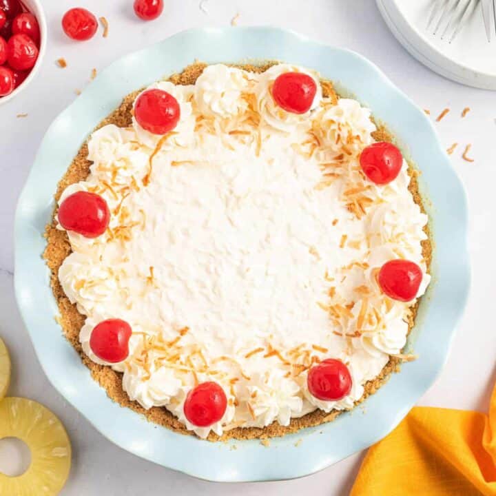 Pineapple pie topped with coconut, whipped cream, and cherries.