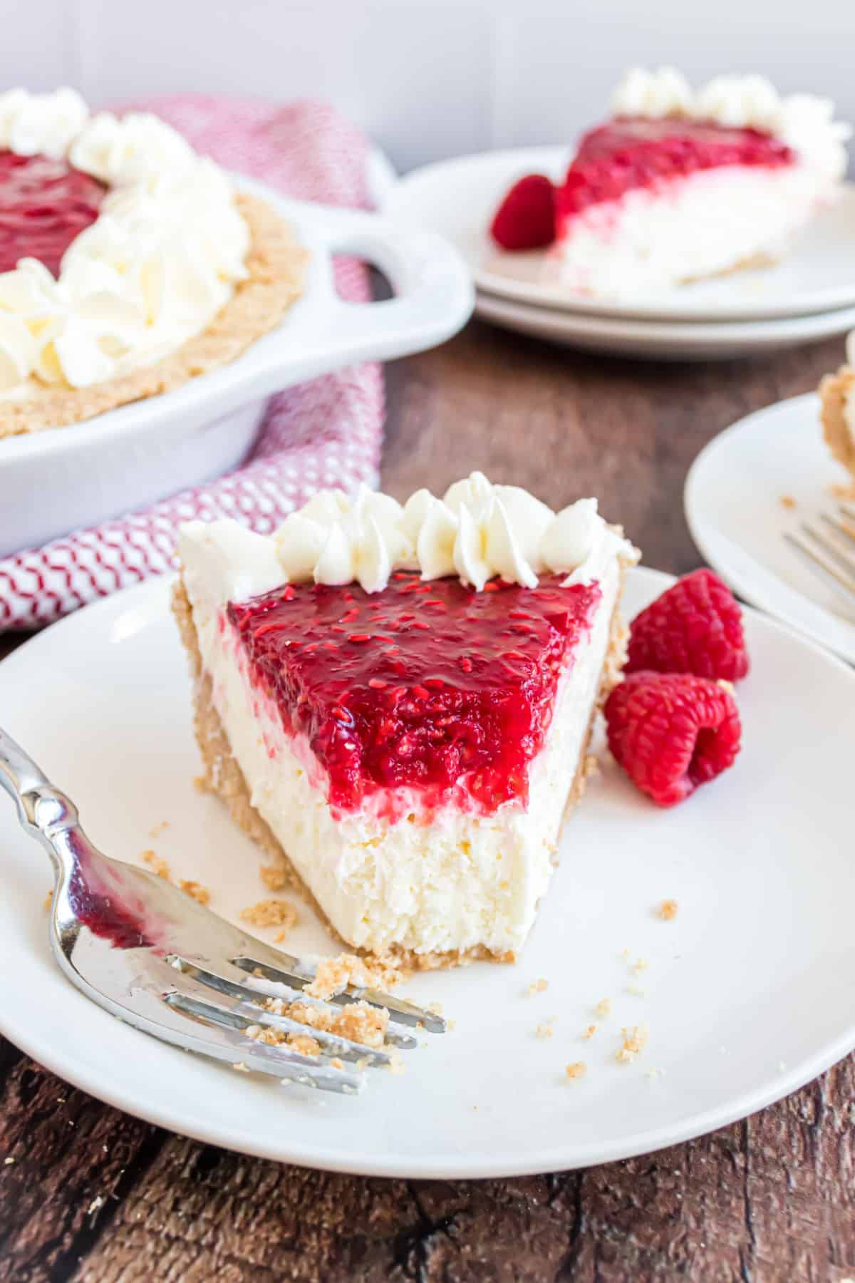 Slice of no bake cheesecake with raspberry fillibg on a white dessert plate.