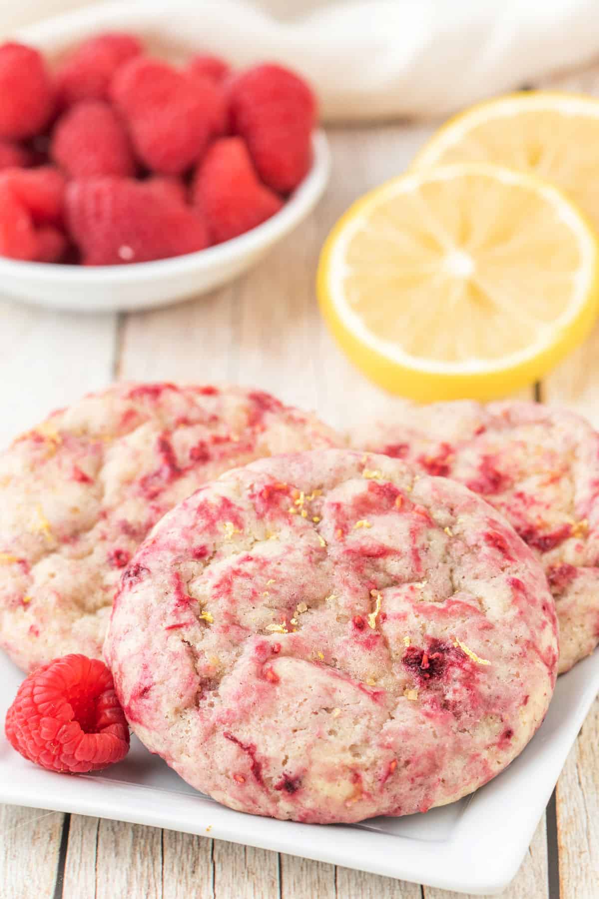 Cookies with raspberries on a white plate.