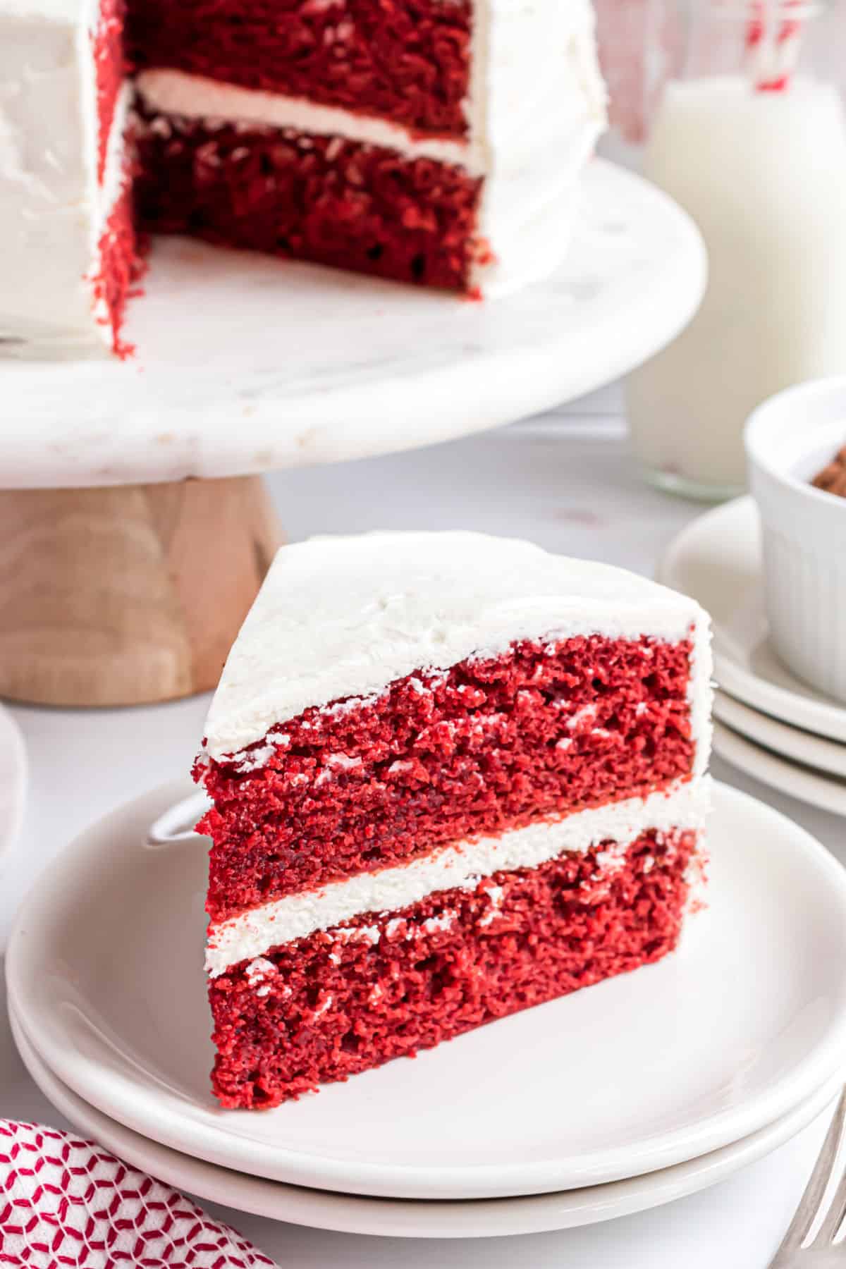 Slice of red velvet cake on a white plate.