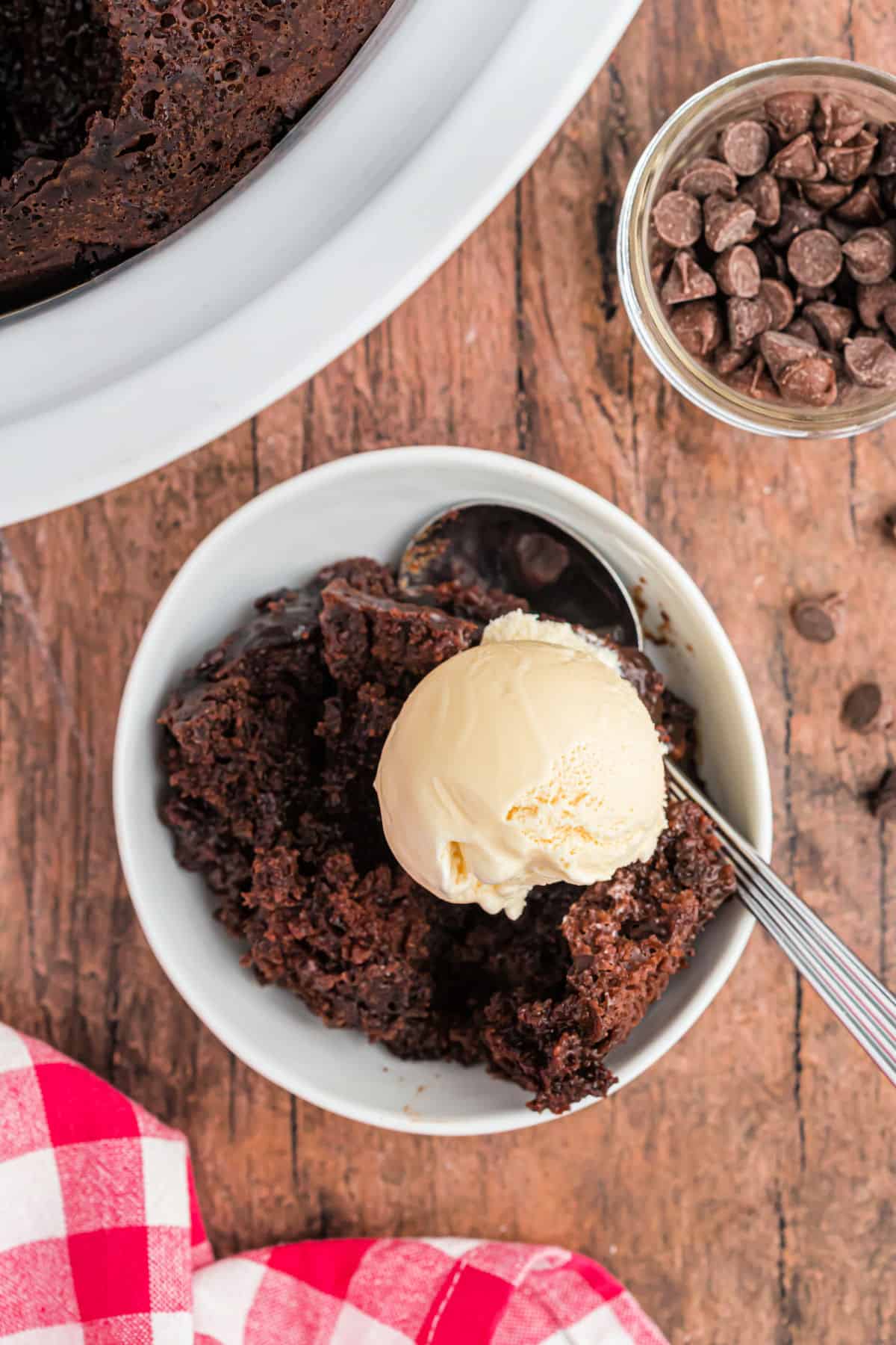 Chocolate spoon cake served in a white bowl with vanilla ice cream.