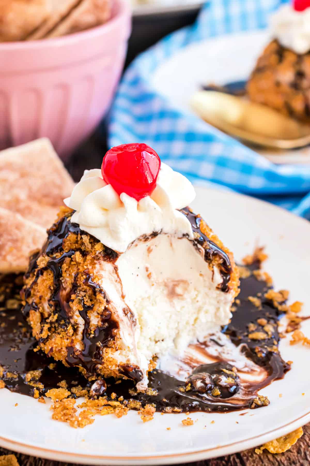 Fried ice cream with chocolate syrup and bite taken out.