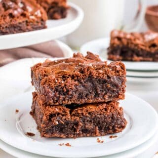 Stack of two brownies on a white plate.