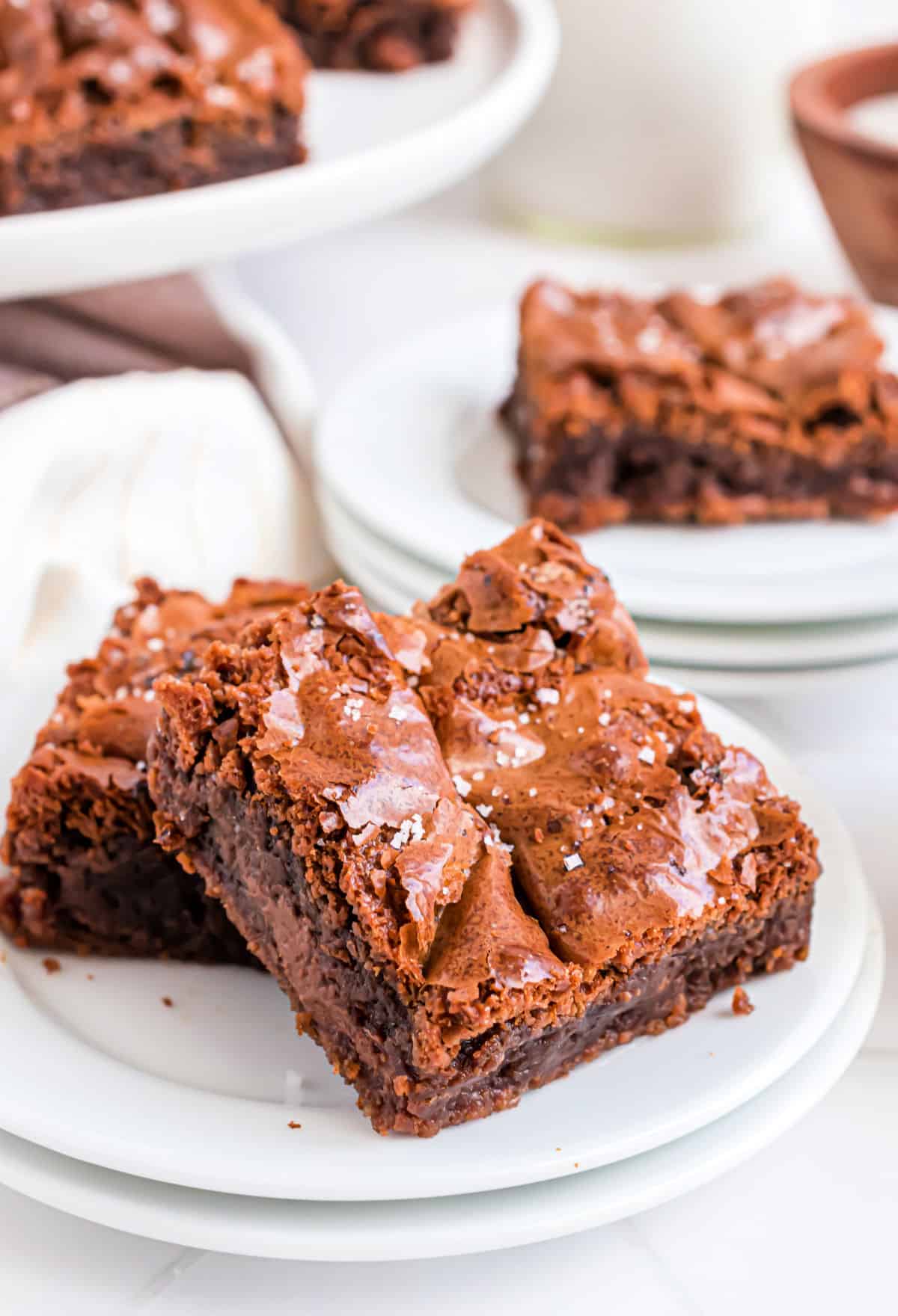 Nutella brownie squares served on a stack of white plates.