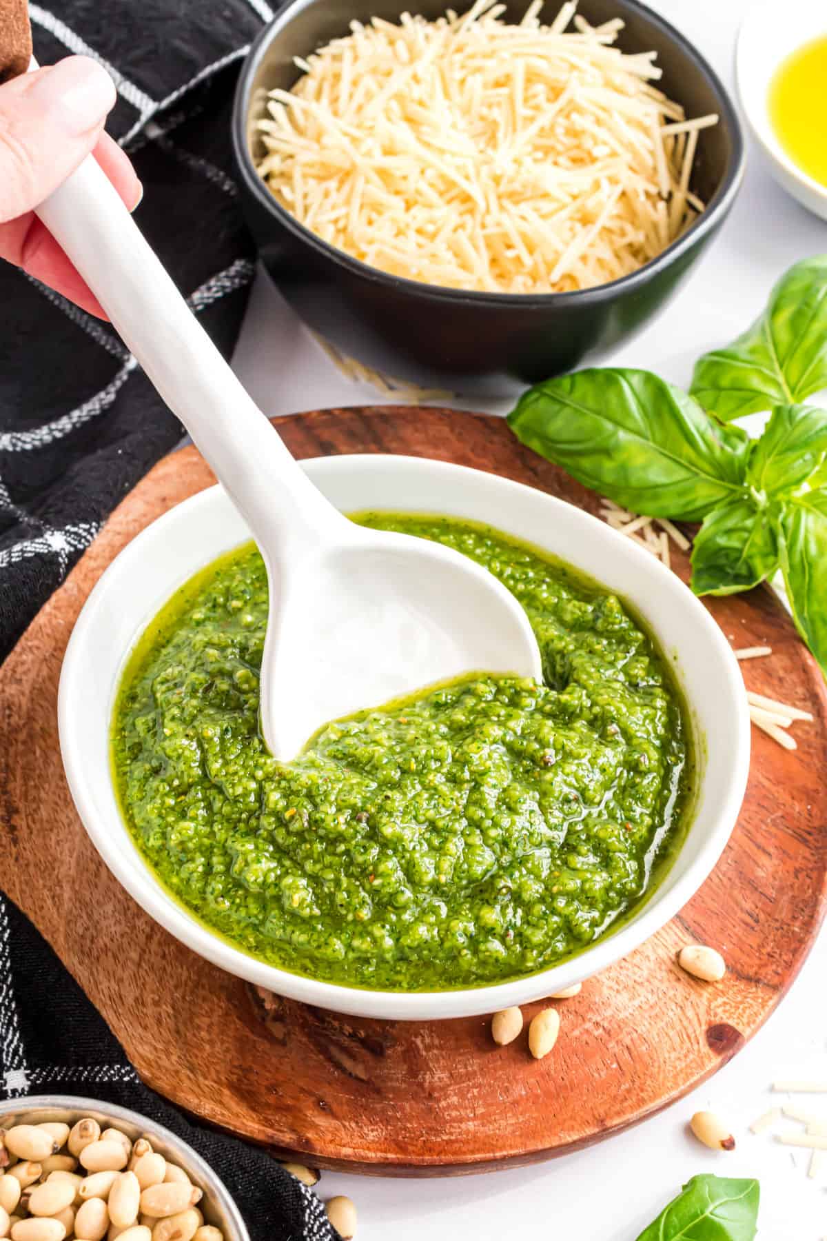 Pesto in a white bowl with a spoon.