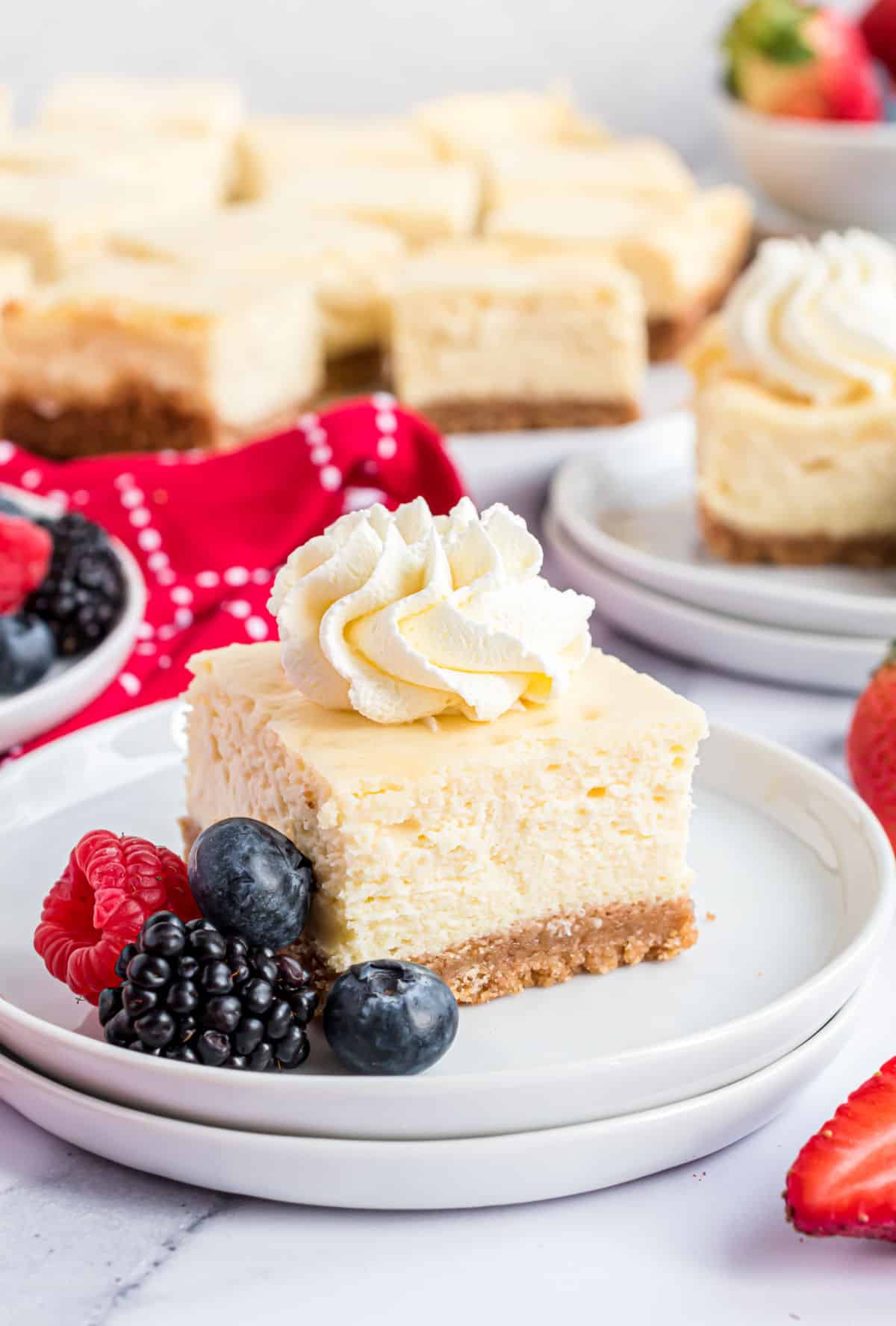 Cheesecake square topped with whipped cream and served with berries.