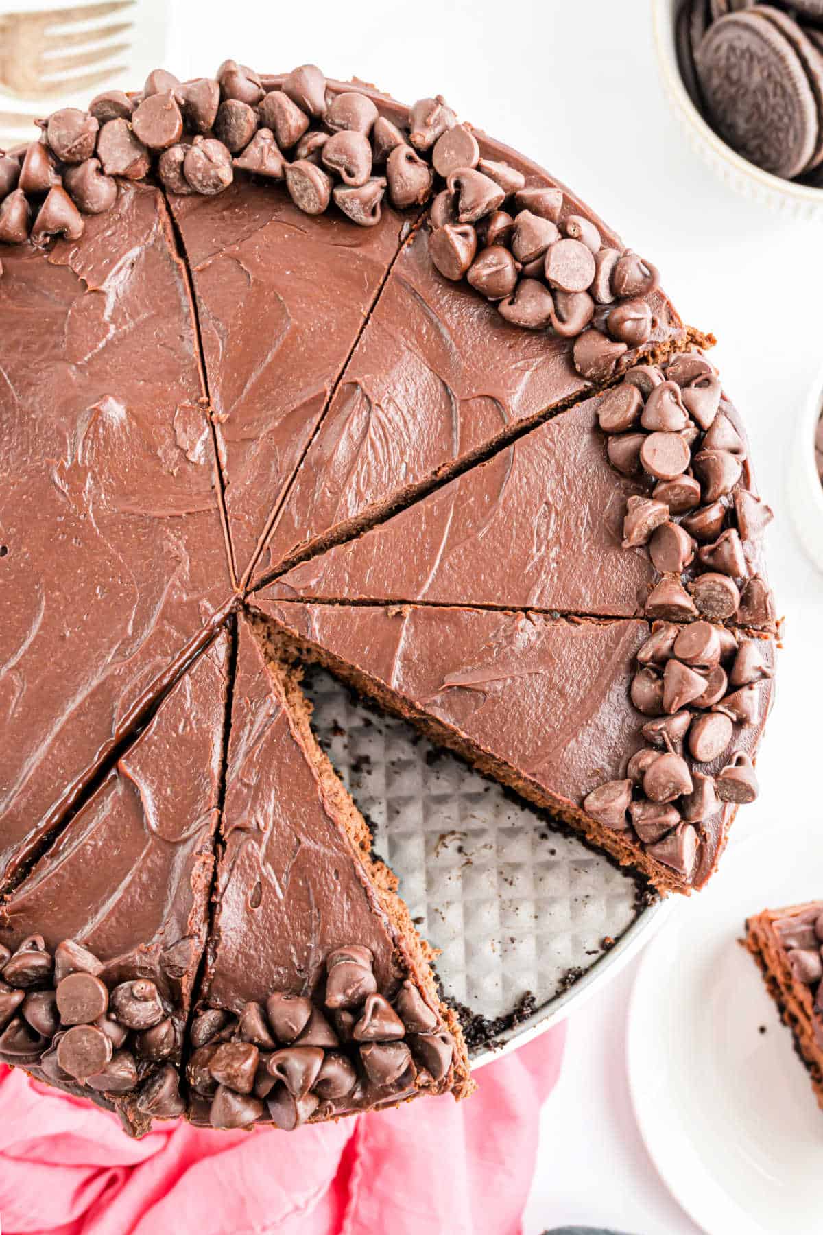 Chocolate cheesecake topped with chocolate chips, sliced with one slice of rich chocolate cheesecake served on a plate.
