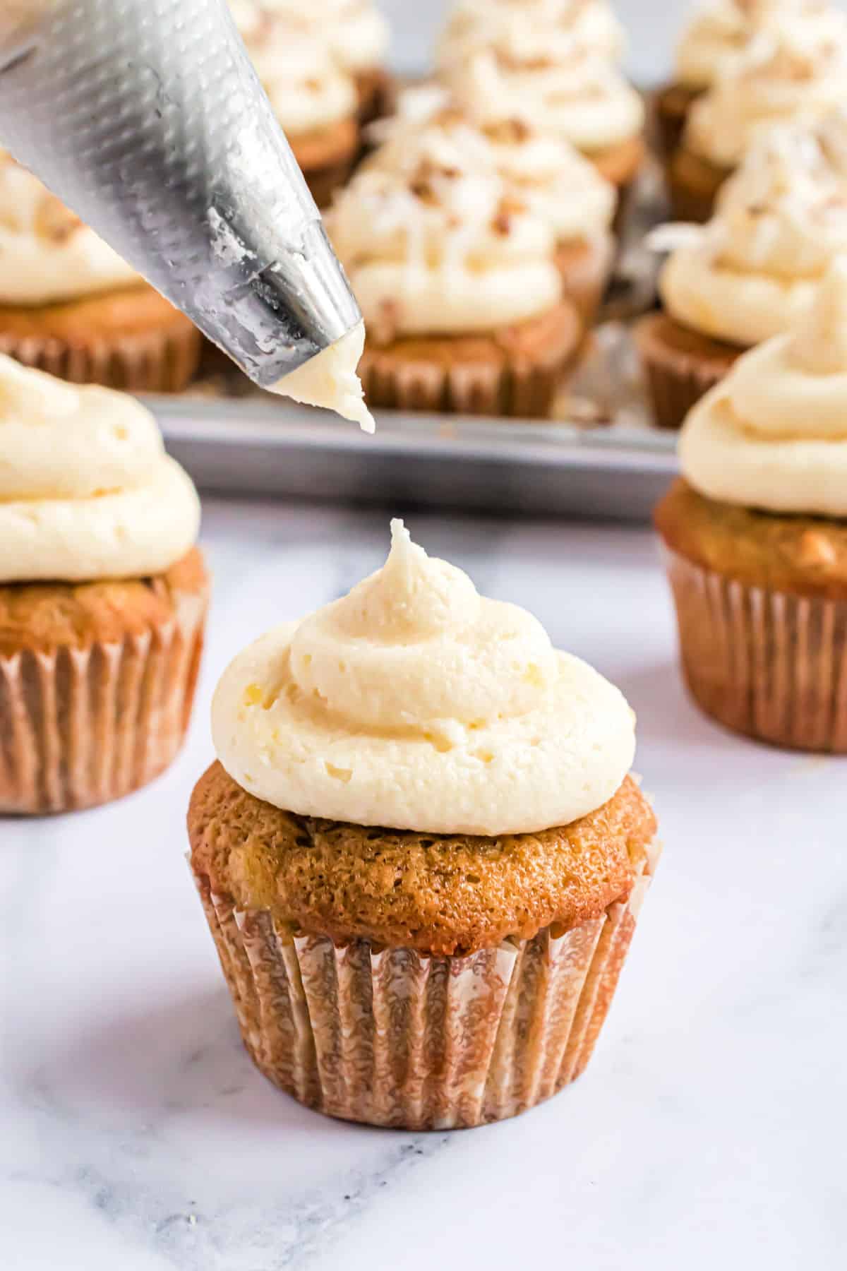 Frosting being piped onto a cupcake.