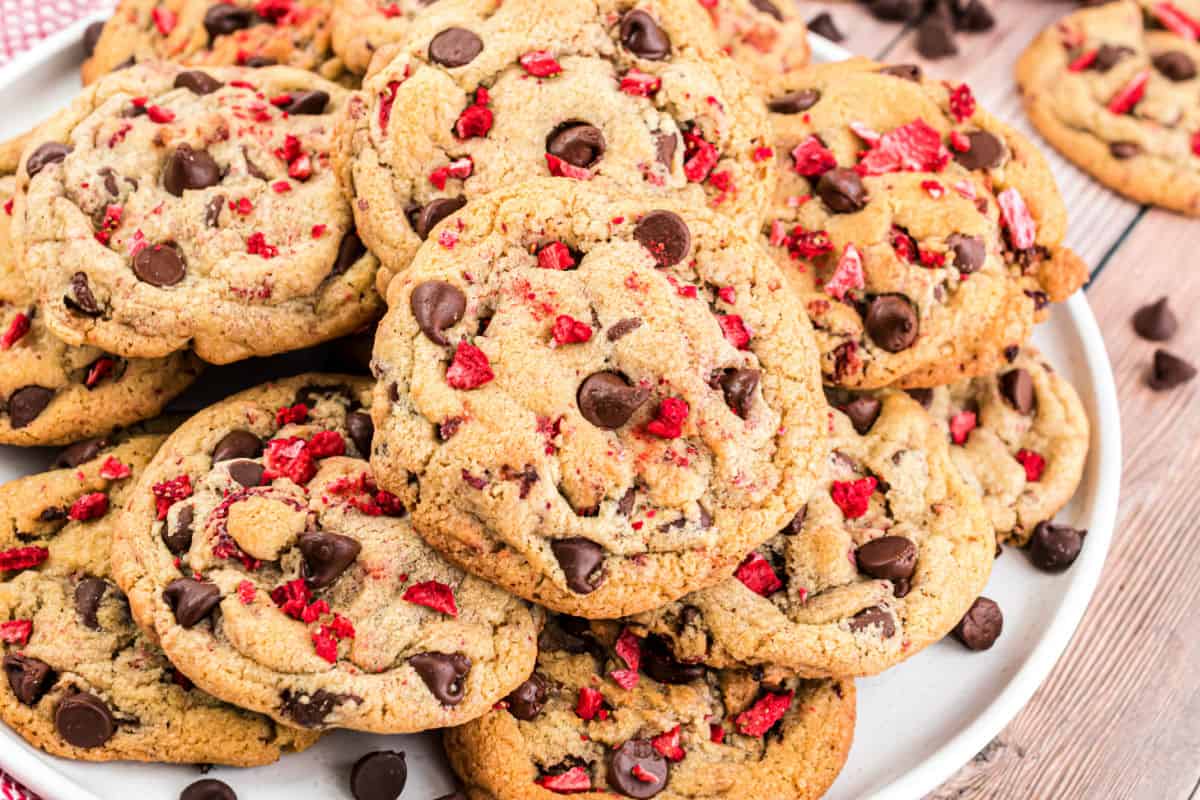 Chocolate chip cookies with strawberries on a large white serving plate.