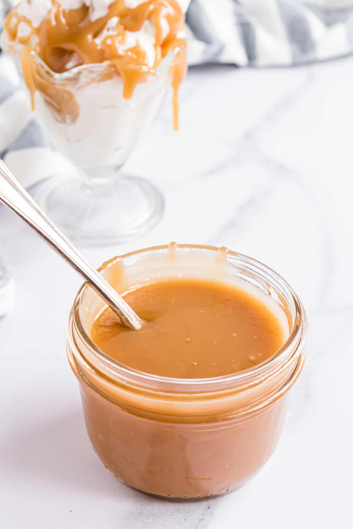 Butterscotch sauce in a jar with a spoon.