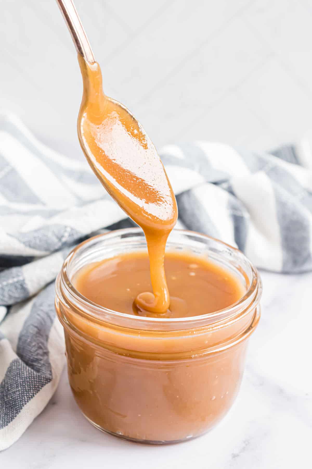 Butterscotch sauce in a small jar and a spoon.