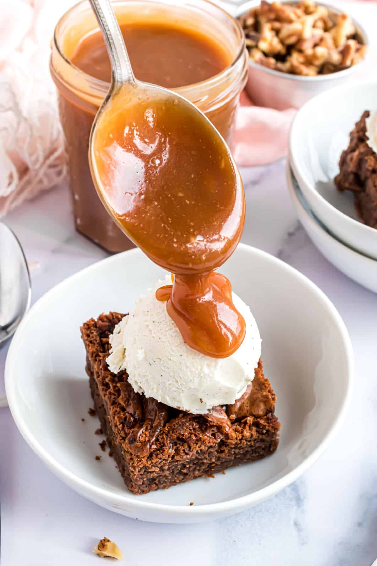 Caramel sauce being drizzled over ice cream and brownies.