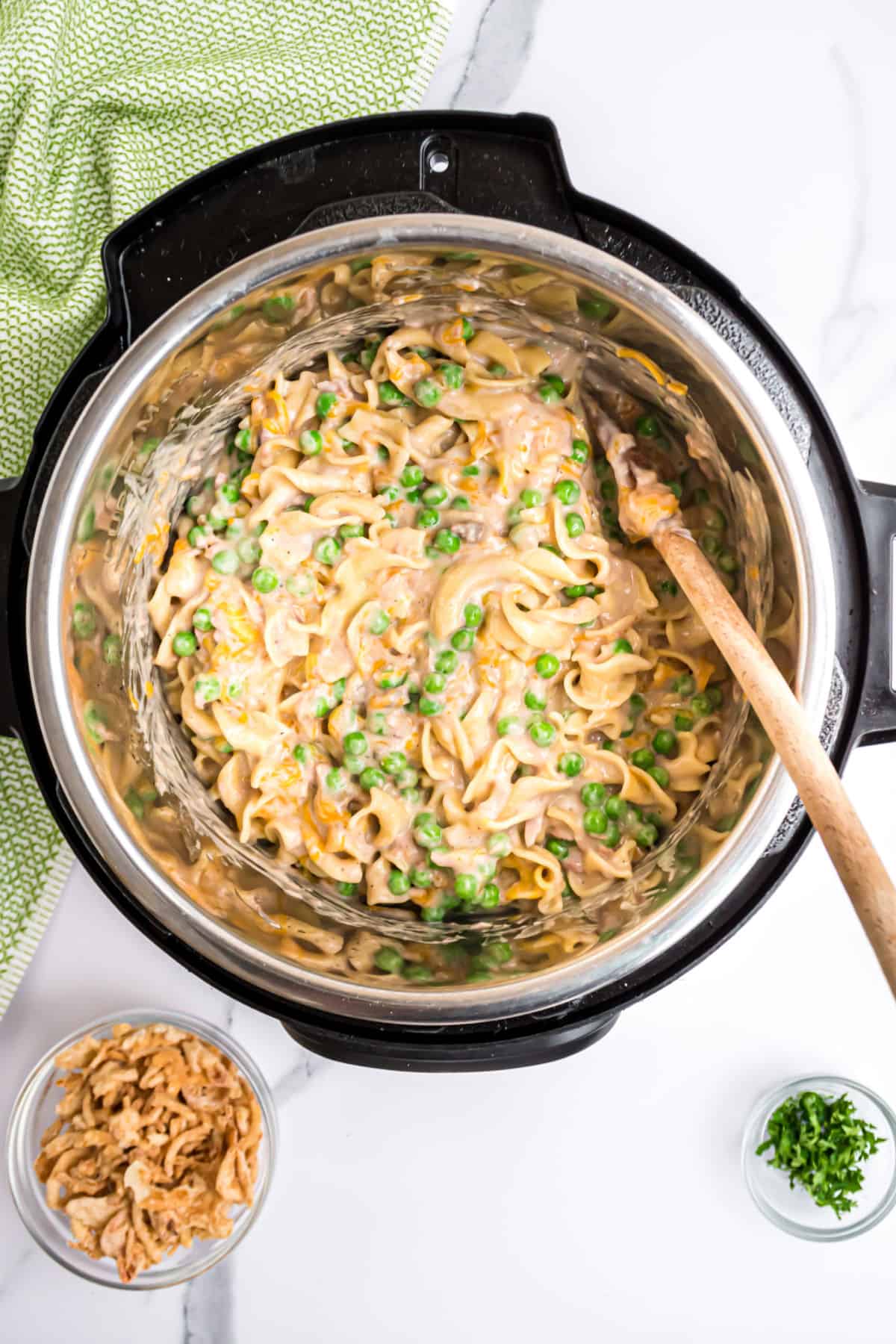 Tuna casserole in the instant pot with a wooden spoon.