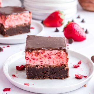 Strawberry frosted brownies on a white plate.