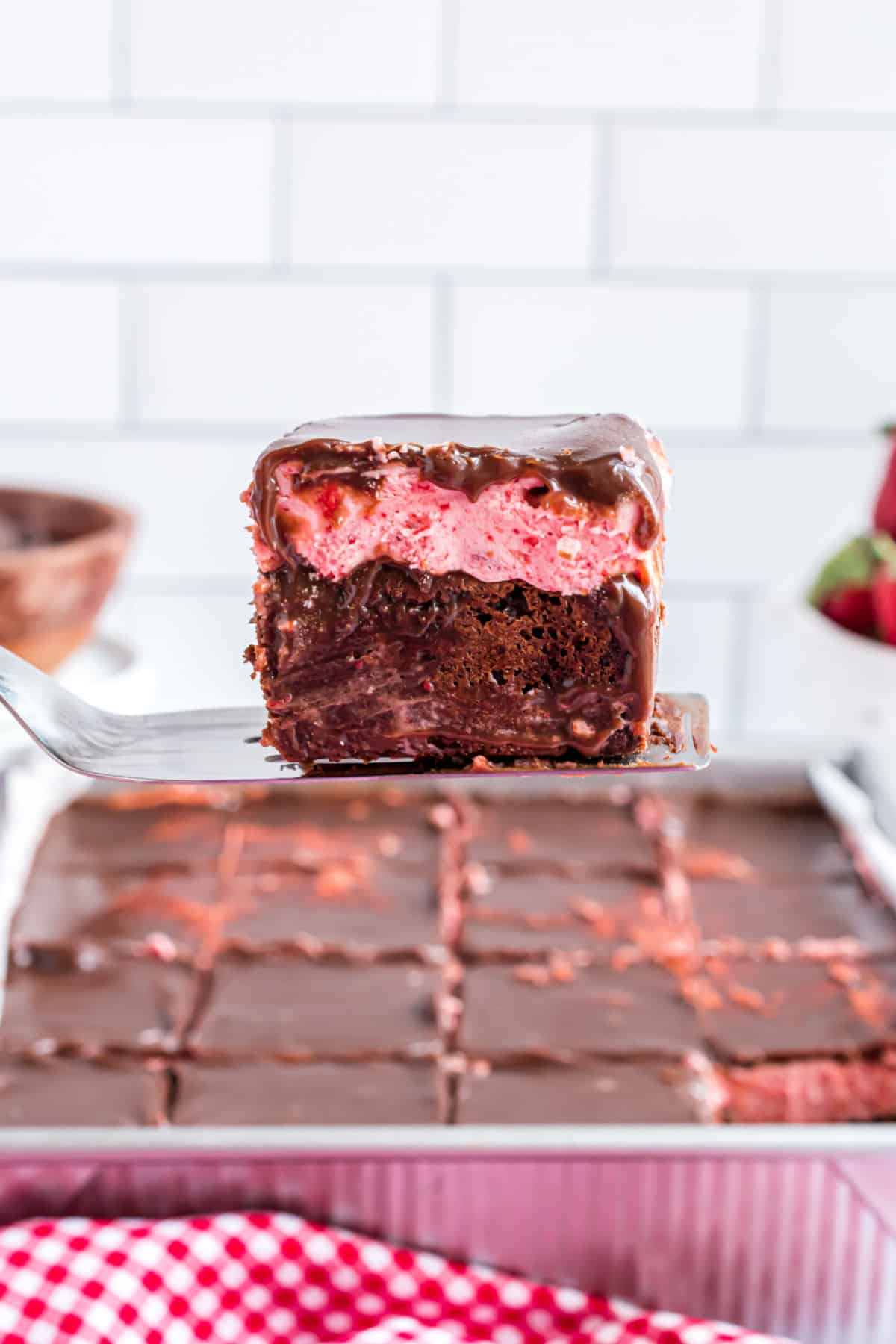 Strawberry brownie being lifted out of baking dish with a spatula.