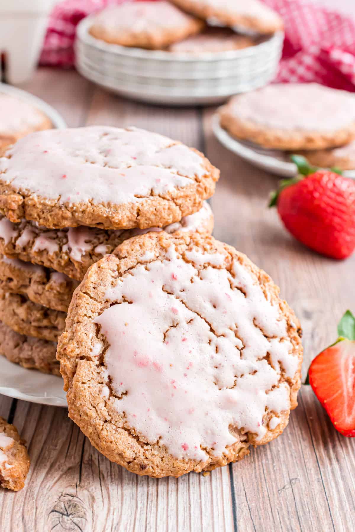 Strawberry iced oatmeal cookies stacked on a plate.