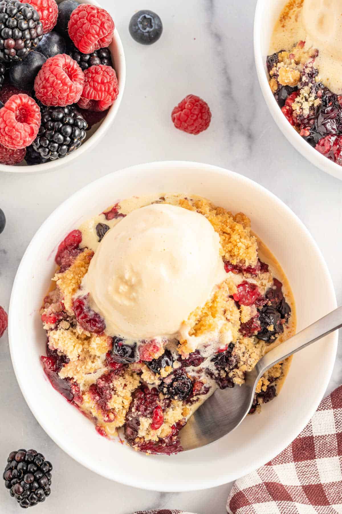 Berry crumble served in a bowl with ice cream.