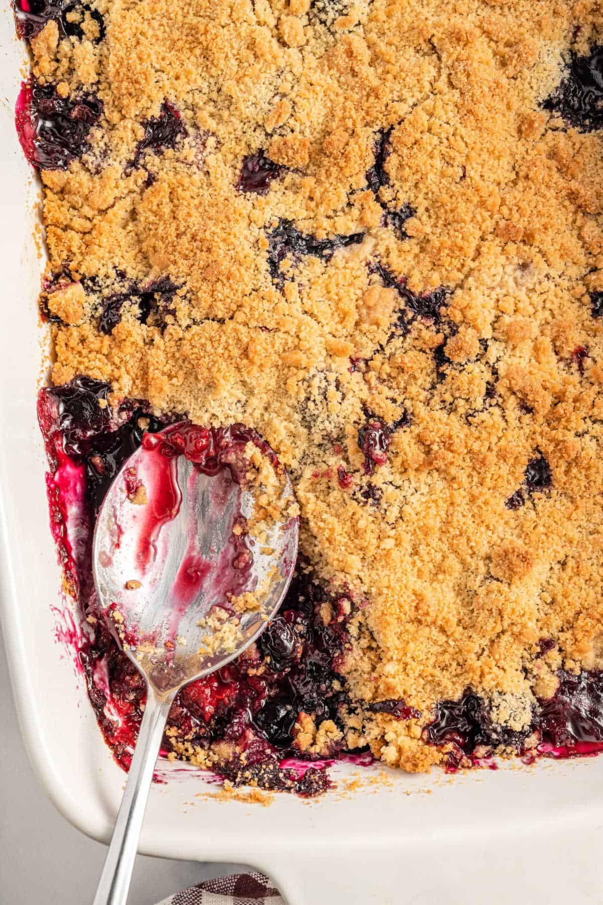 Berry crumble in a dish with a spoon.
