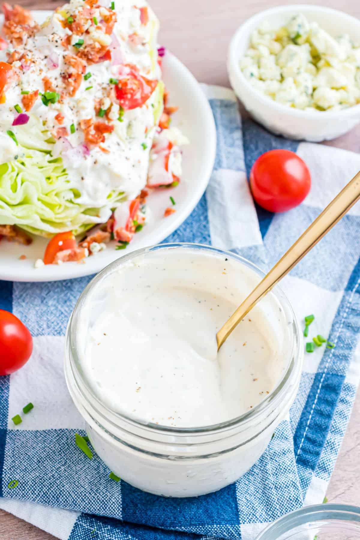 Blue cheese dressing in a jar with a wedge salad in background.