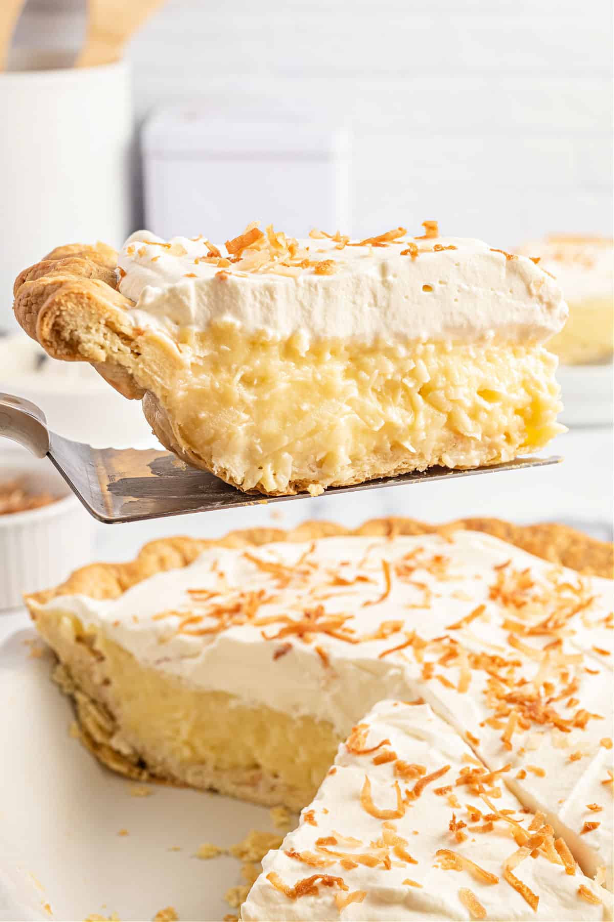 Slice of coconut cream pie being lifted out of pie plate.