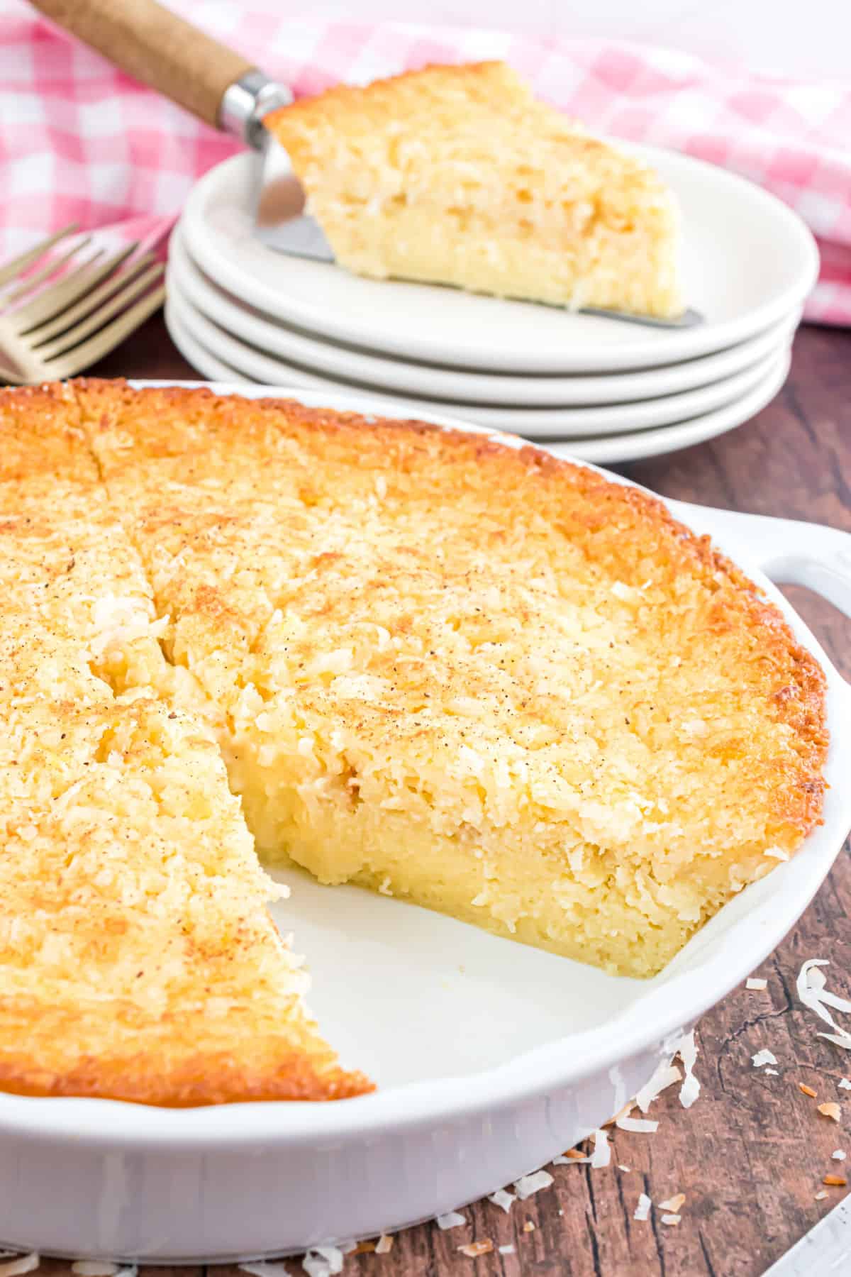 Slice of coconut pie removed from a white pie plate.