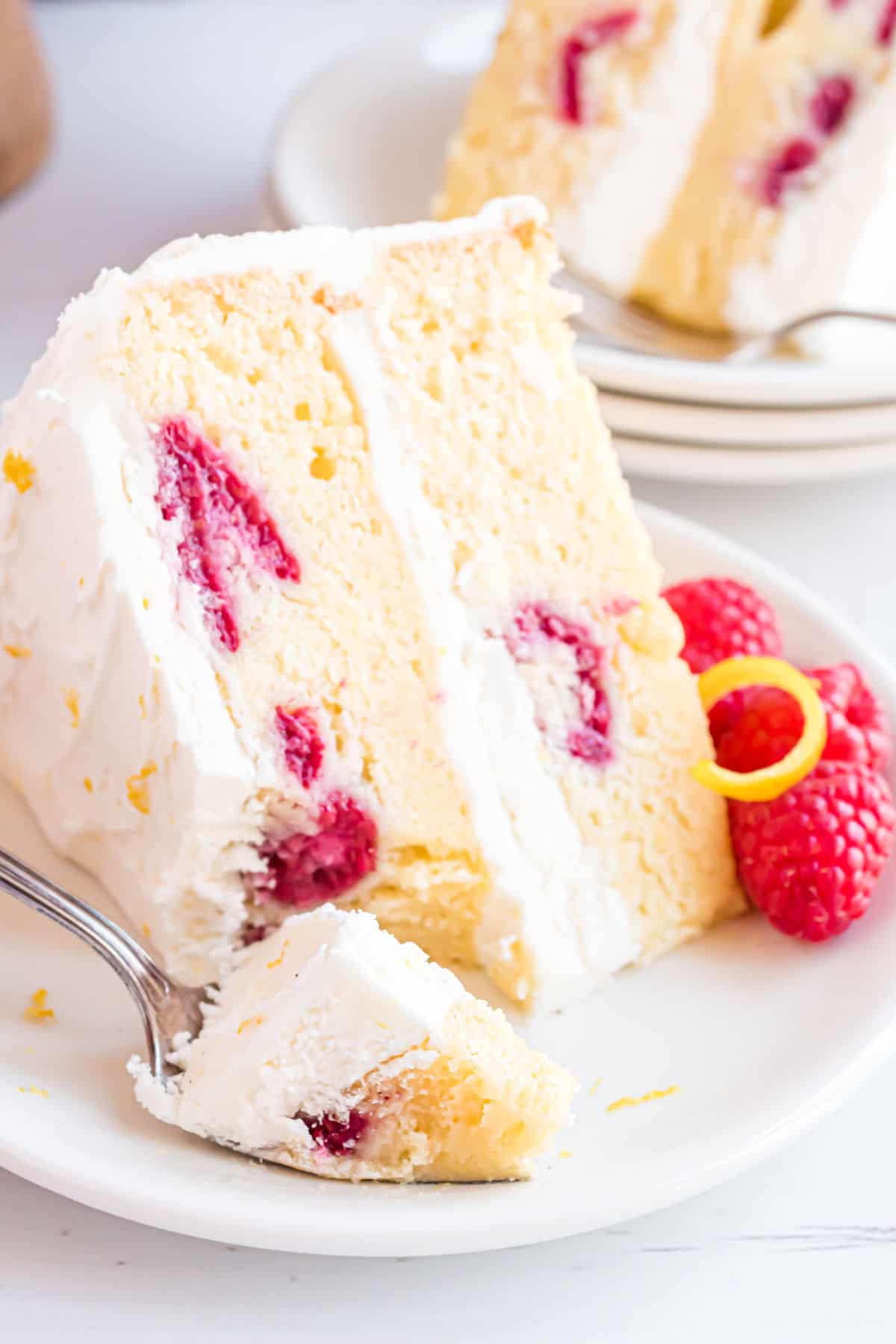 Slice of cake with raspberries with a bite taken out.