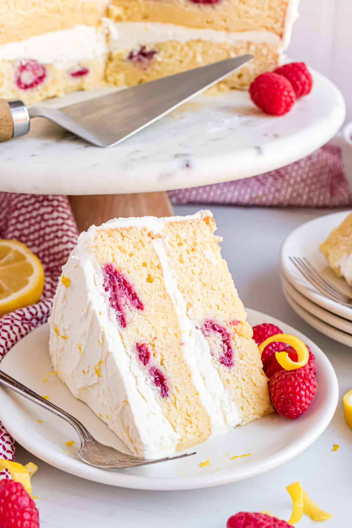 Slice of raspberry lemon layer cake with creamy lemon frosting.